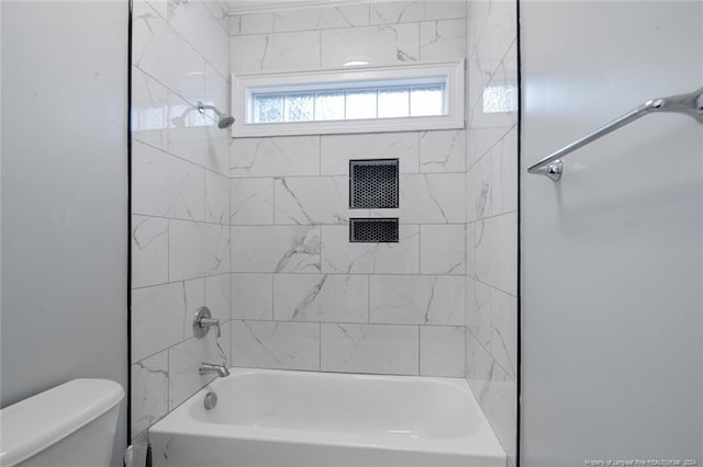 bathroom with tiled shower / bath combo and toilet