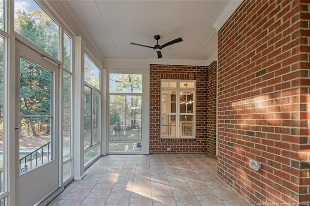 unfurnished sunroom featuring ceiling fan and a healthy amount of sunlight