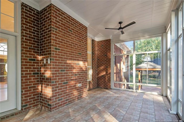unfurnished sunroom featuring ceiling fan and a healthy amount of sunlight