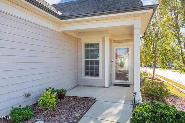 view of exterior entry featuring roof with shingles