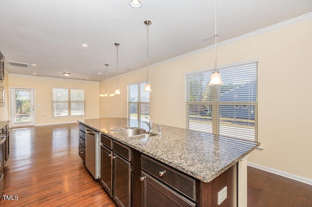 kitchen featuring light stone counters, a sink, a center island with sink, and decorative light fixtures