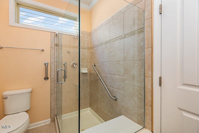 bathroom with baseboards, a stall shower, toilet, and crown molding