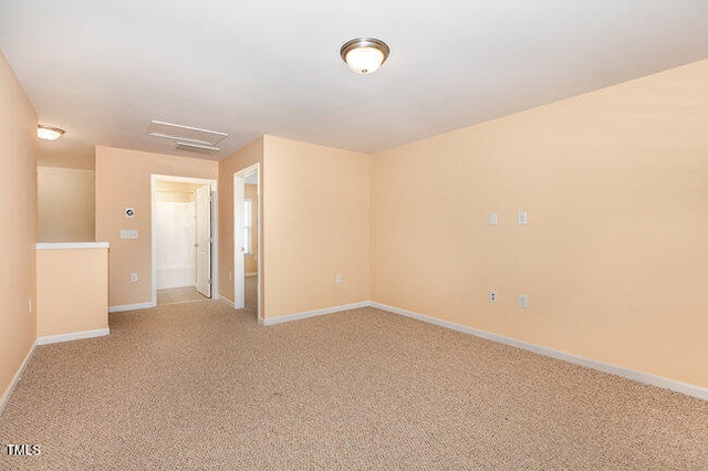 empty room with light carpet, attic access, and baseboards