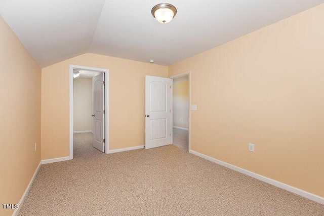 unfurnished bedroom featuring light carpet, a spacious closet, and baseboards