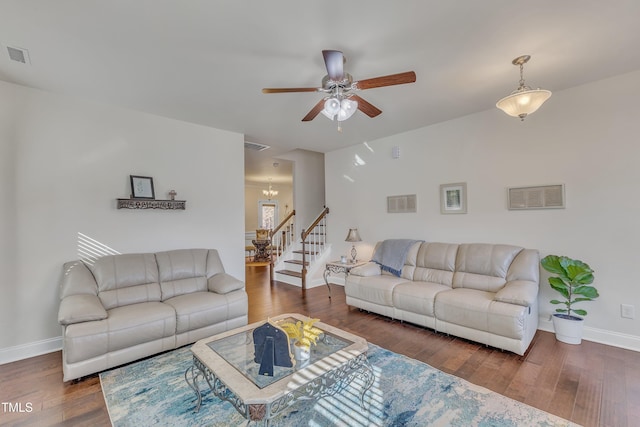 living room featuring dark wood-type flooring and ceiling fan with notable chandelier