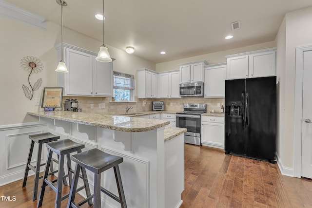 kitchen with dark wood-type flooring, pendant lighting, white cabinets, and stainless steel appliances