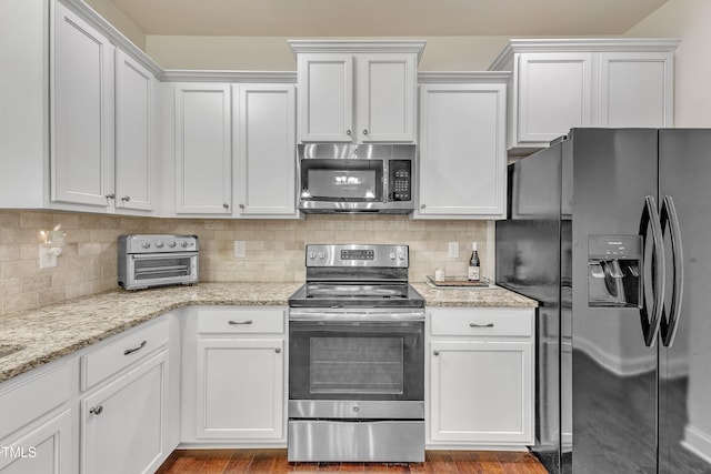 kitchen with backsplash, white cabinetry, and stainless steel appliances