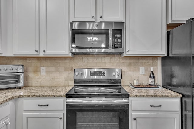 kitchen featuring white cabinets, light stone countertops, appliances with stainless steel finishes, and tasteful backsplash