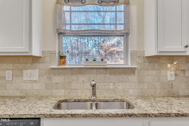 kitchen featuring white cabinets, light stone counters, dishwasher, and sink