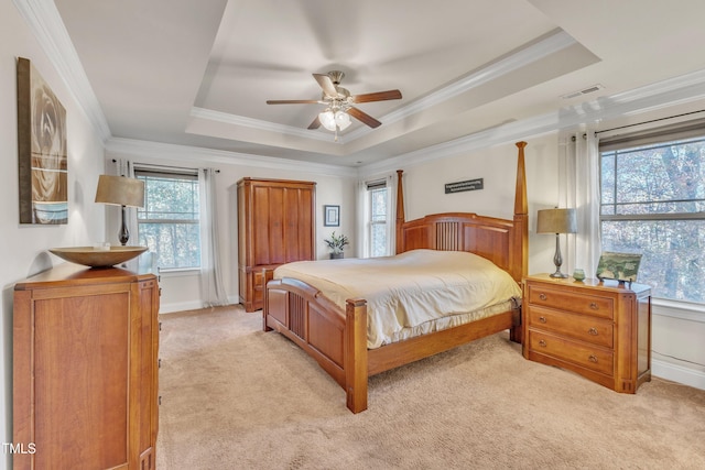 carpeted bedroom featuring a raised ceiling, multiple windows, and ceiling fan