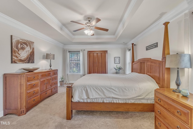 carpeted bedroom with a tray ceiling, ceiling fan, and crown molding