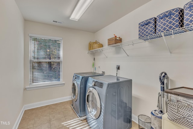 laundry area with light tile patterned floors and washing machine and clothes dryer