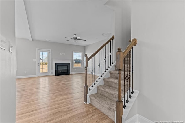 staircase with hardwood / wood-style flooring and ceiling fan