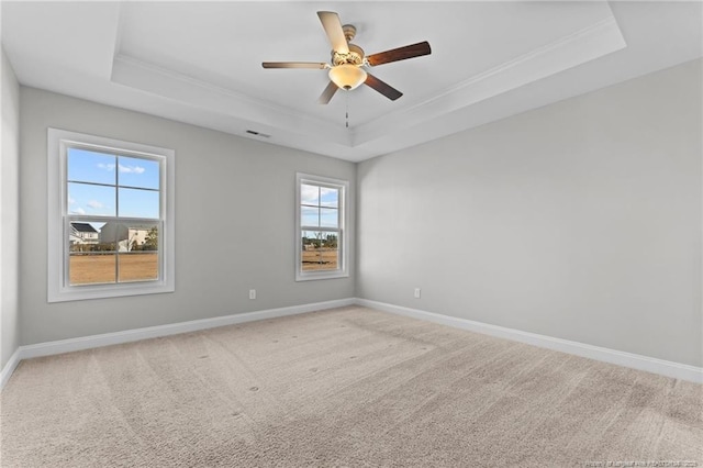 carpeted empty room with ceiling fan and a tray ceiling