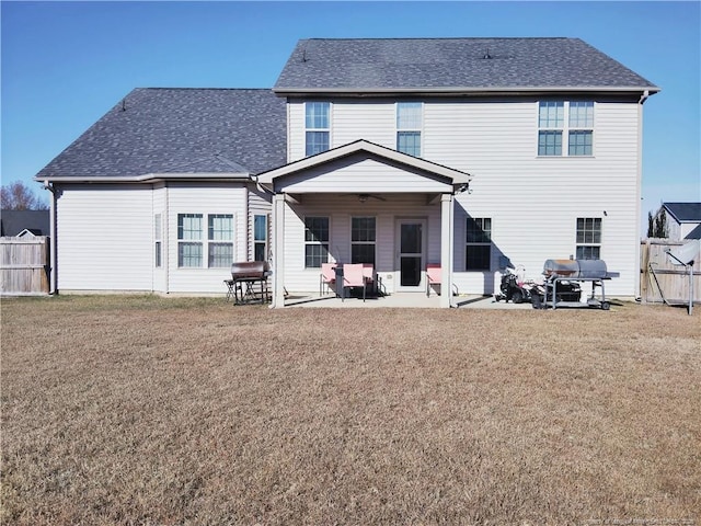 rear view of property with a patio area, roof with shingles, fence, and a yard