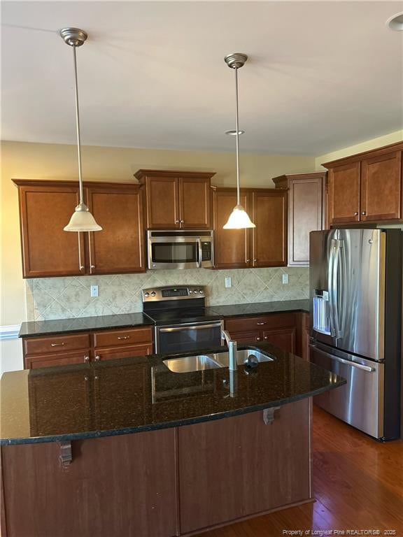 kitchen featuring appliances with stainless steel finishes, dark wood-type flooring, a sink, and decorative backsplash