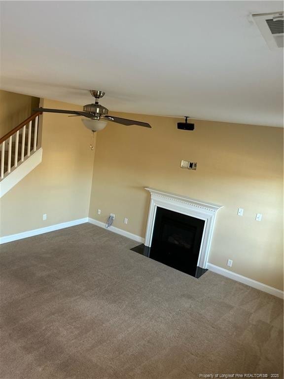 unfurnished living room featuring a fireplace with flush hearth, carpet flooring, baseboards, and stairs