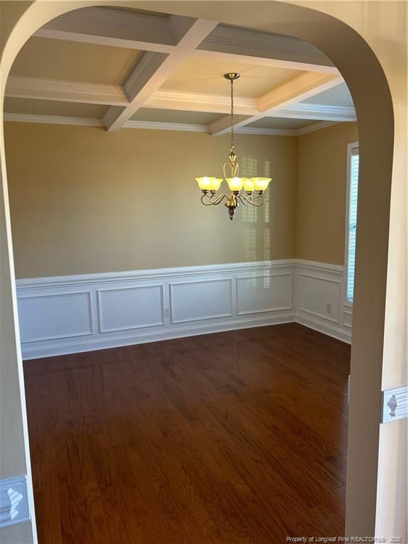 empty room featuring arched walkways, a chandelier, dark wood-style flooring, coffered ceiling, and beam ceiling