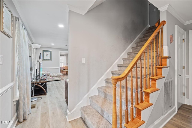 stairway with crown molding and hardwood / wood-style floors