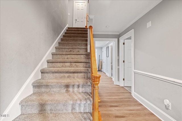 staircase with wood-type flooring and ornamental molding