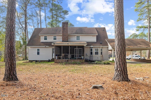 rear view of house featuring a sunroom, a yard, and a carport