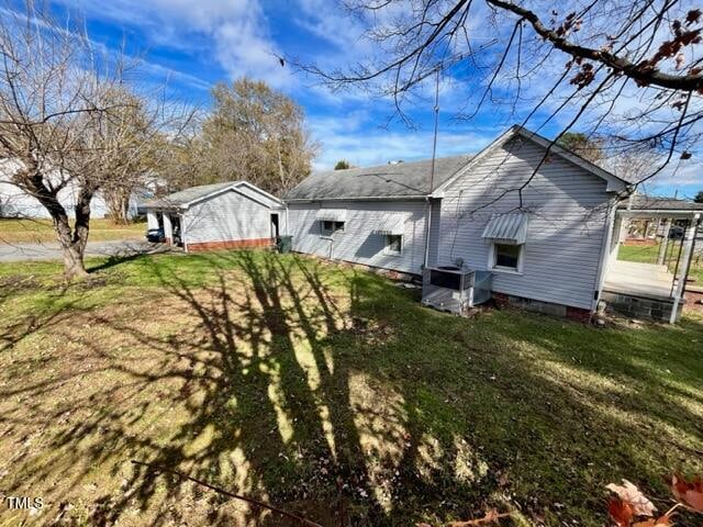 view of side of home featuring central AC and a yard