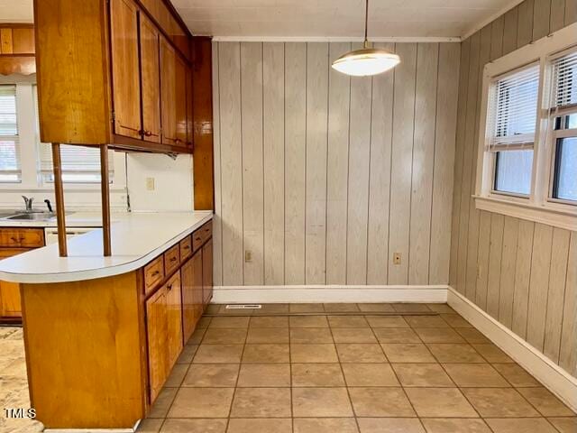 kitchen featuring kitchen peninsula, wood walls, light tile patterned floors, and decorative light fixtures