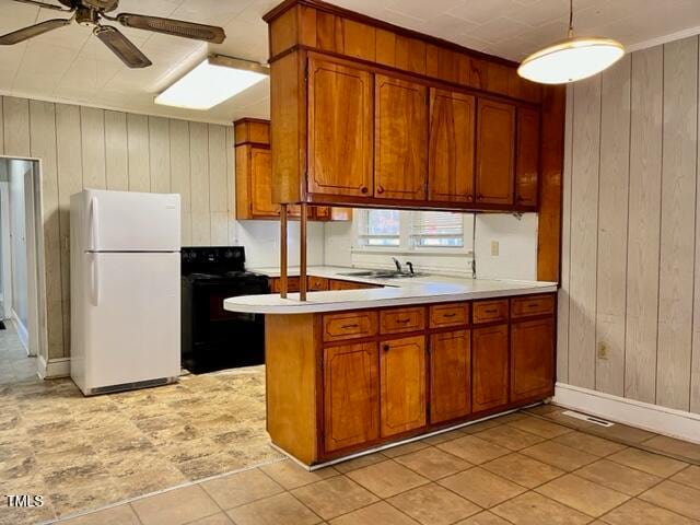 kitchen with sink, white refrigerator, black / electric stove, and wood walls