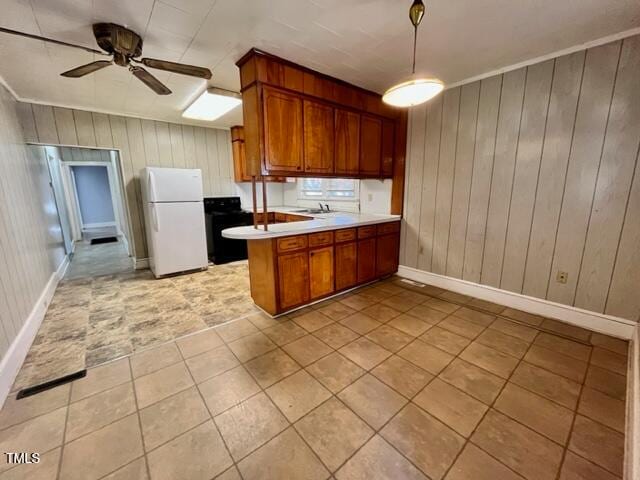 kitchen featuring wood walls, black range oven, ceiling fan, white fridge, and kitchen peninsula