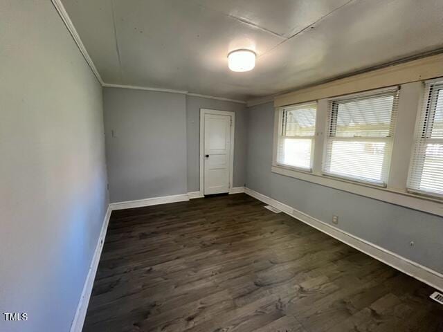 spare room with dark hardwood / wood-style floors, a wealth of natural light, and crown molding