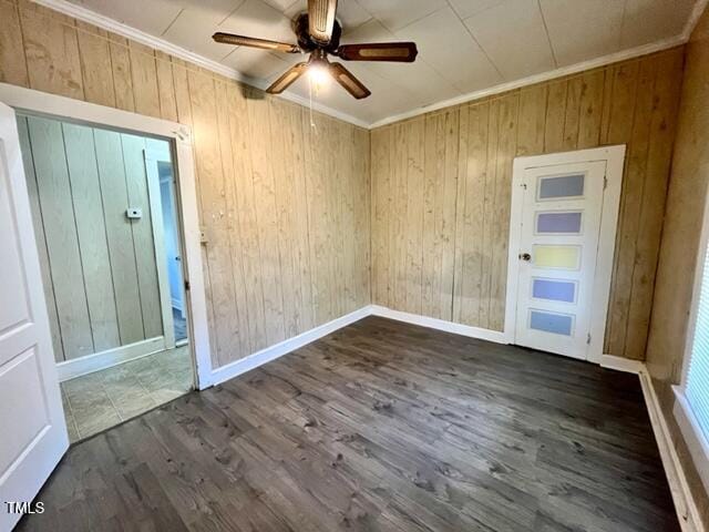 spare room featuring ceiling fan, wood walls, crown molding, and dark wood-type flooring