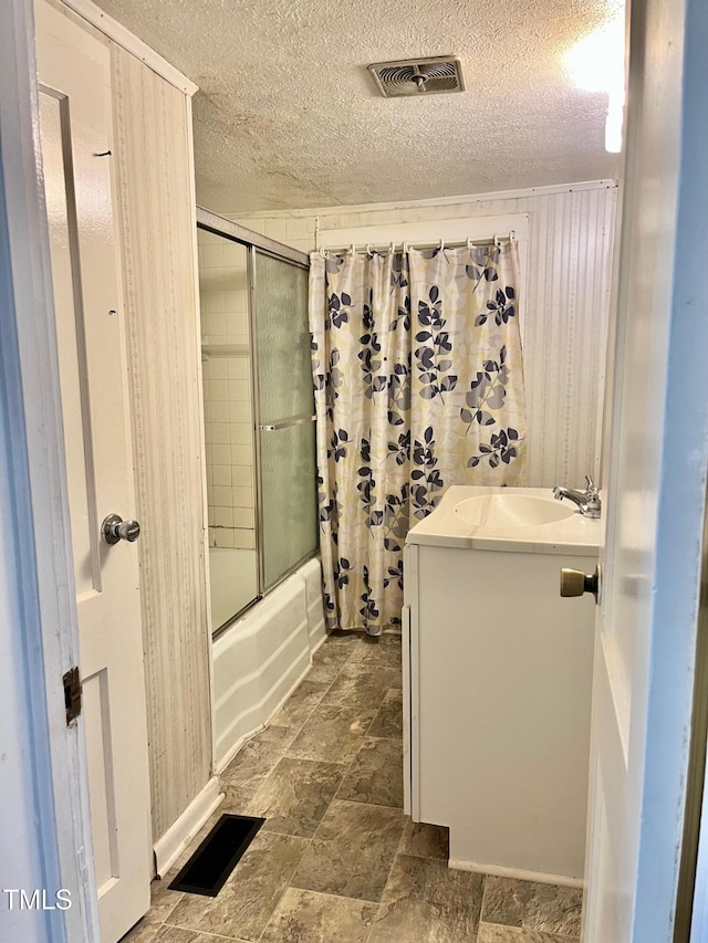 bathroom with vanity, shower / bath combination with glass door, and a textured ceiling