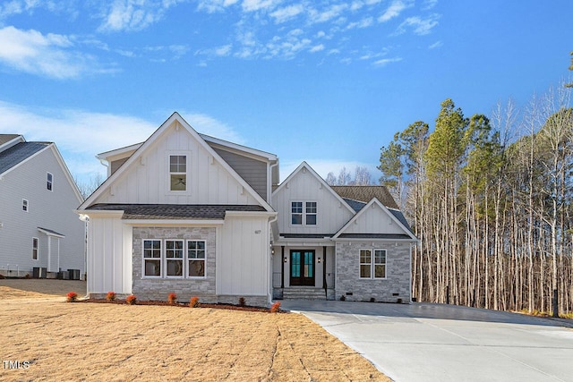 view of front of property with central air condition unit, stone siding, board and batten siding, and a shingled roof