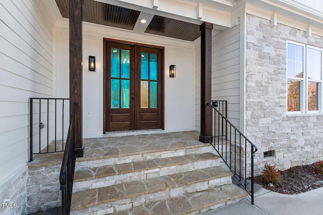 entrance to property with crawl space, stone siding, and french doors