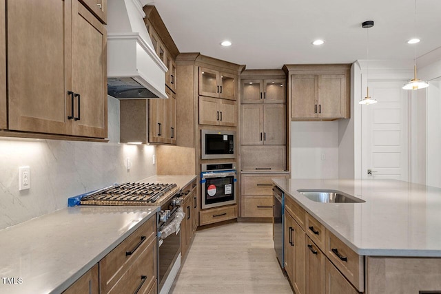 kitchen featuring light stone countertops, pendant lighting, appliances with stainless steel finishes, custom exhaust hood, and light hardwood / wood-style floors