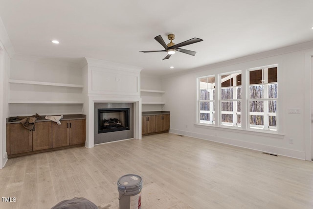 unfurnished living room featuring ceiling fan, a fireplace, crown molding, and light hardwood / wood-style flooring