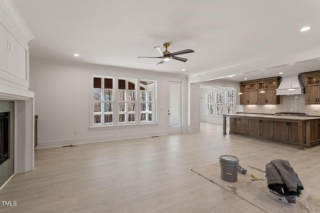 unfurnished living room featuring ceiling fan, light hardwood / wood-style floors, and crown molding