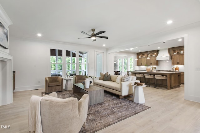 living area featuring a ceiling fan, light wood finished floors, crown molding, recessed lighting, and baseboards