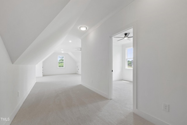 additional living space with ceiling fan, lofted ceiling, light colored carpet, and baseboards