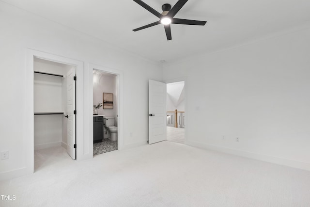 unfurnished bedroom featuring a spacious closet, carpet floors, ensuite bathroom, a closet, and baseboards