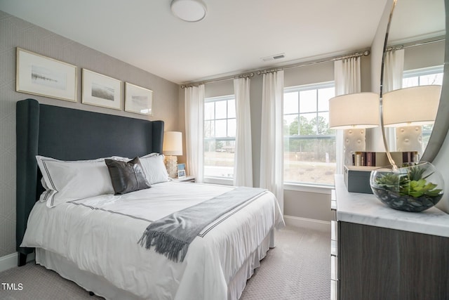 bedroom with multiple windows and light colored carpet