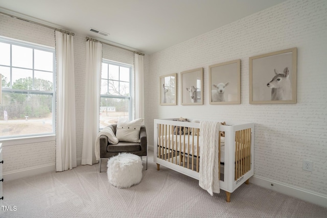 bedroom featuring carpet flooring, a crib, and brick wall