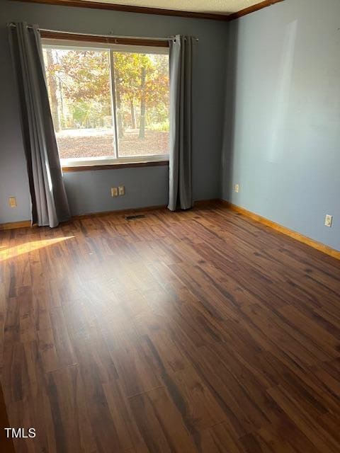 unfurnished room featuring ornamental molding and dark wood-type flooring