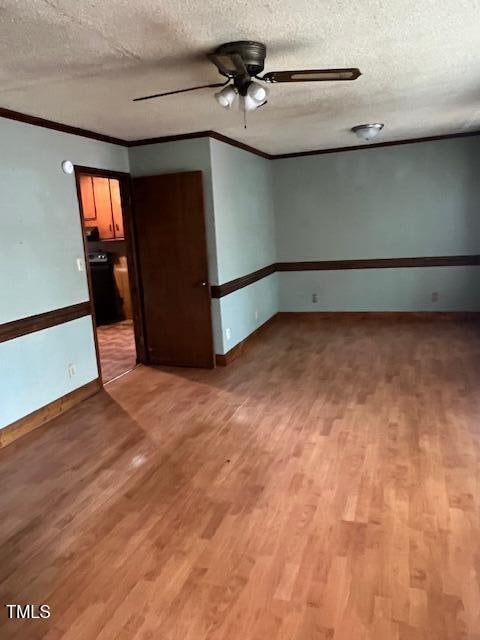 empty room with a textured ceiling, light hardwood / wood-style floors, ceiling fan, and ornamental molding