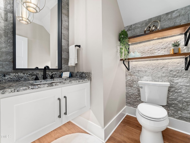 bathroom featuring a chandelier, wood-type flooring, lofted ceiling, toilet, and vanity