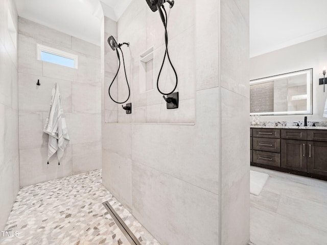 bathroom with vanity, a tile shower, and ornamental molding