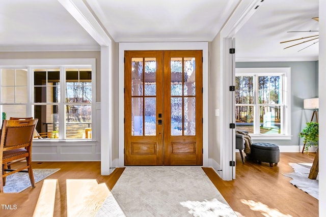 entryway with ceiling fan, light wood-type flooring, ornamental molding, and french doors