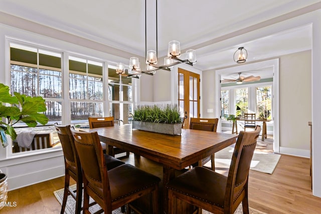 dining space featuring french doors, ceiling fan with notable chandelier, and light hardwood / wood-style flooring