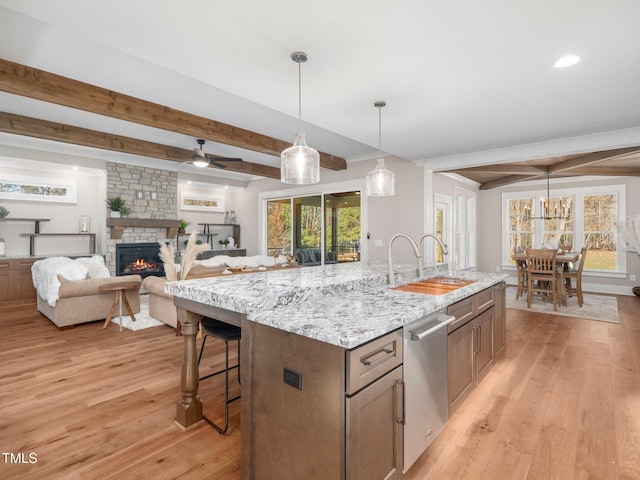 145 Wiggins Rd, Louisburg, NC 27549 - kitchen featuring stainless steel dishwasher, beam ceiling, light wood-style flooring, a kitchen island with sink, and decorative light fixtures