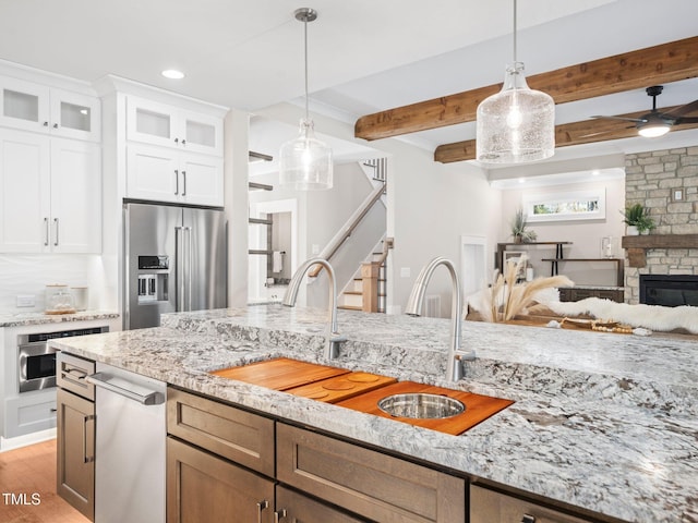 kitchen with stainless steel appliances, ceiling fan, sink, white cabinetry, and hanging light fixtures